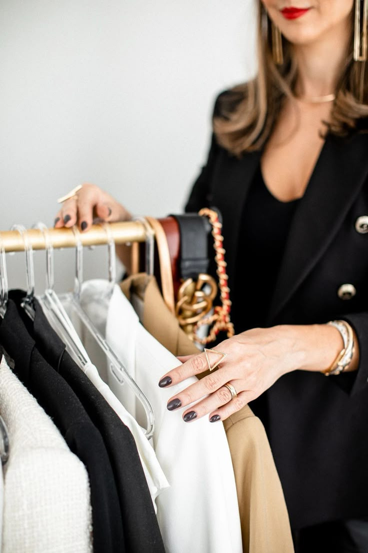 Manos organizando prendas en un rack de ropa